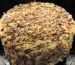 Tall round layer cake covered in toasted nuts with a chocolate drizzle, similar to this german chocolate cake recipe