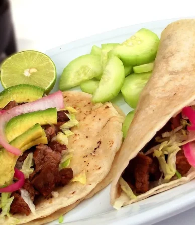 Two steak tacos with avocado, pickled red onion and lime on corn tortillas, similar to this steak tacos recipe