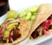 Two steak tacos with avocado, pickled red onion and lime on corn tortillas, similar to this steak tacos recipe