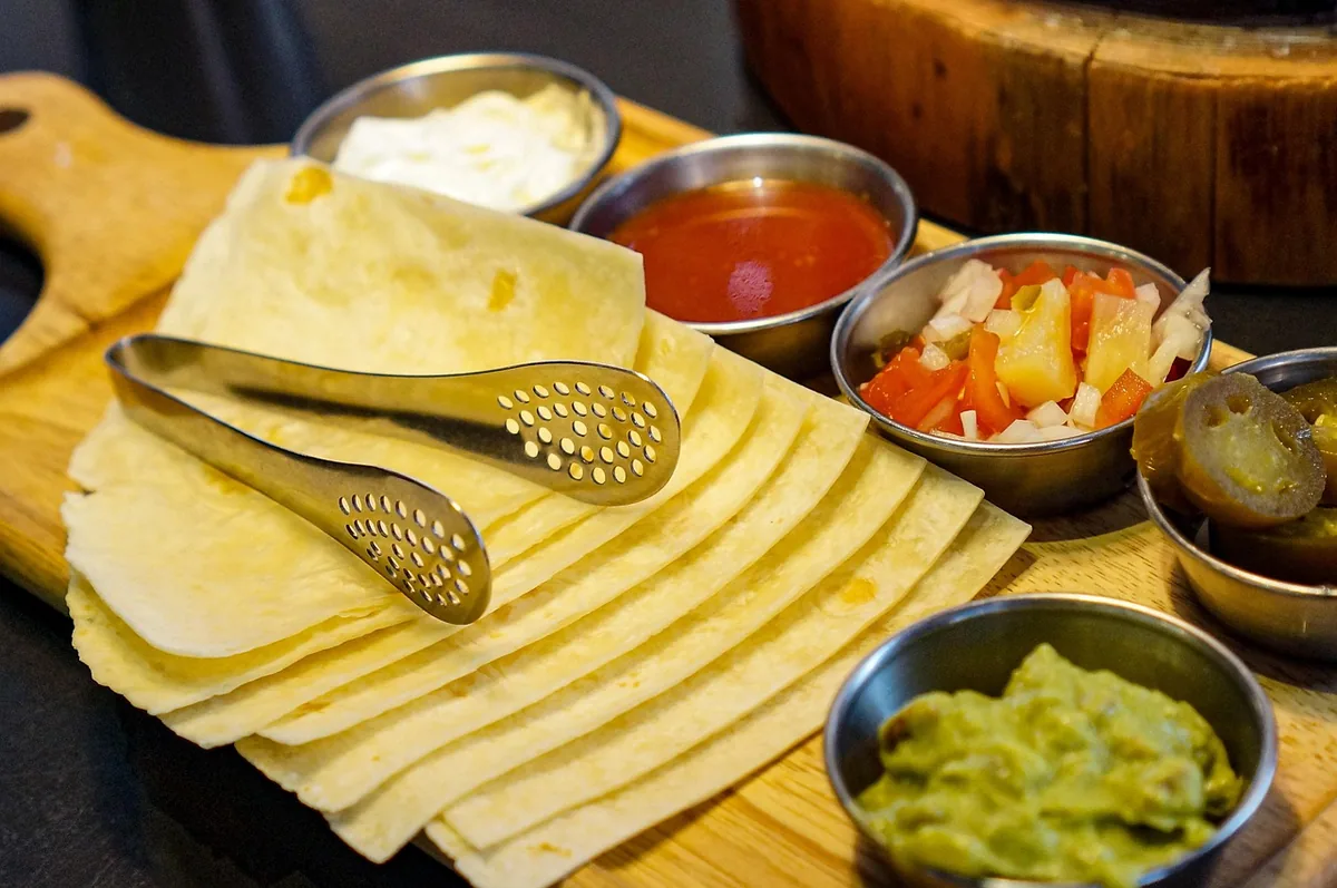 Warm tortillas with guacamole, salsa, sour cream and jalapeños for a steak taco bar