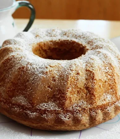 Golden Bundt cake dusted with powdered sugar on a plate, similar to this buttermilk pound cake recipe