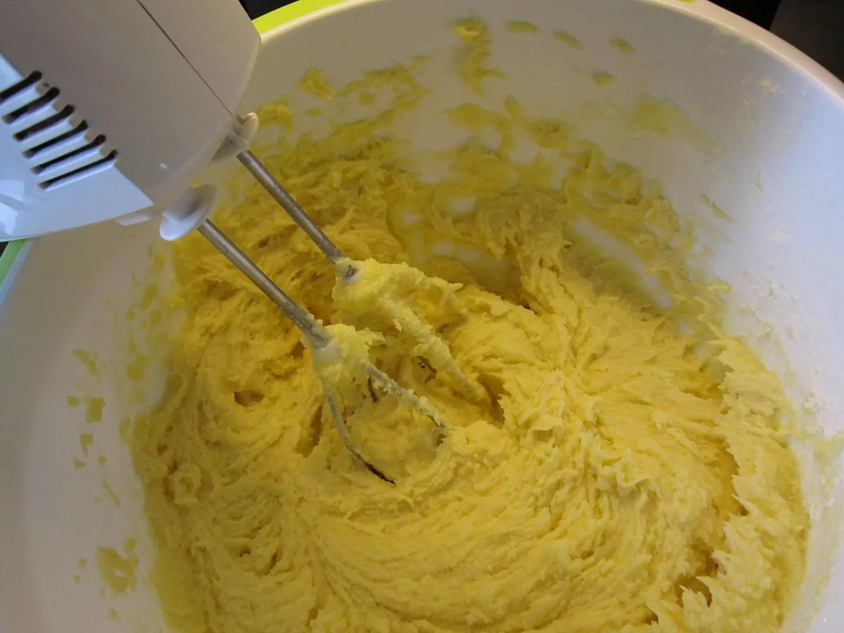 Hand mixer beating thick, pale yellow pound cake batter in a white bowl