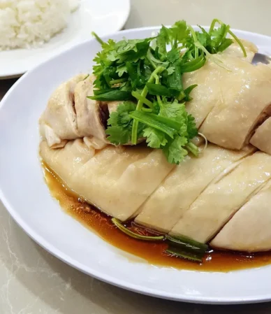 Sliced poached chicken with cilantro on a white plate, similar to boiled chicken breast cooked for the right time