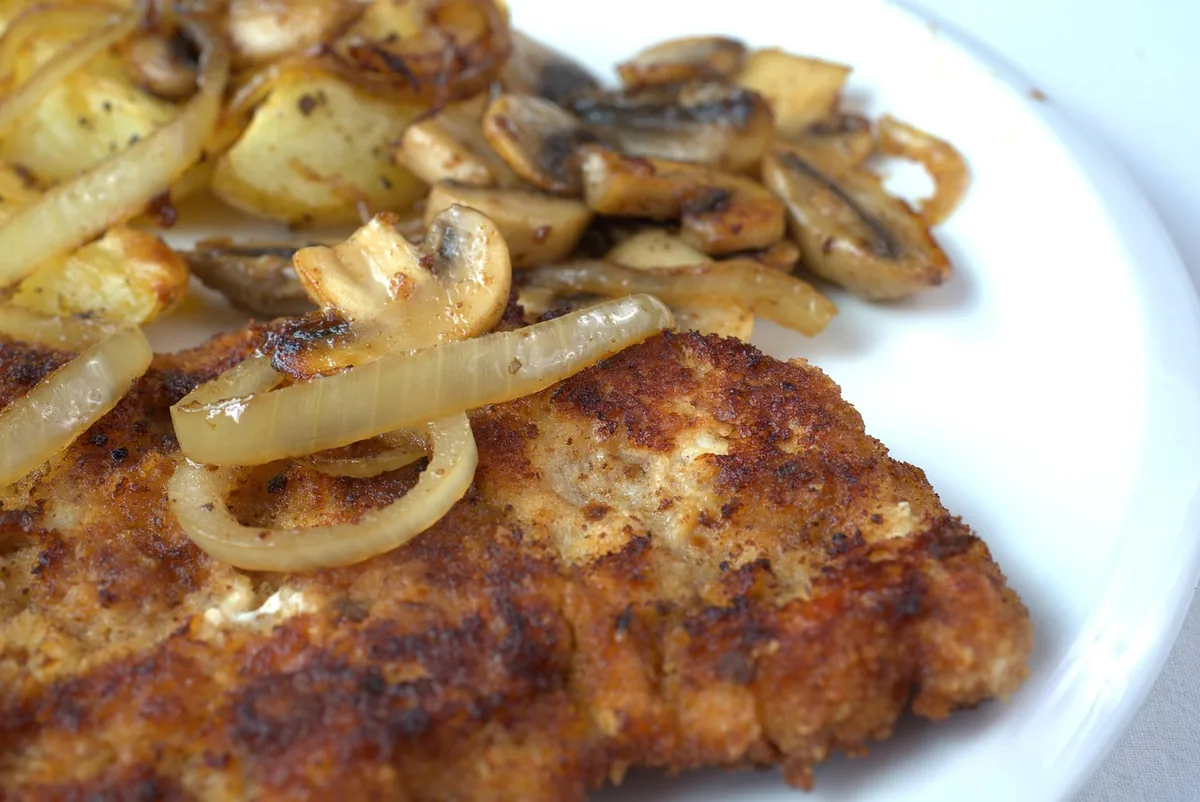 Crisp fried steak topped with golden onions, served with fried potatoes and mushrooms