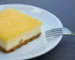 Square of lemon-topped cream cheese dessert on a white plate with a fork, similar to a lemon cream cheese dump cake