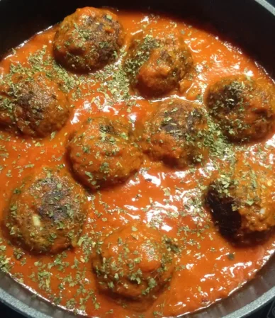 Meatballs simmering in tomato sauce in a skillet, similar to these homemade meatballs, showing how to make meatballs in sauce