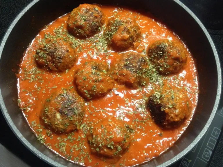 Meatballs simmering in tomato sauce in a skillet, similar to these homemade meatballs, showing how to make meatballs in sauce