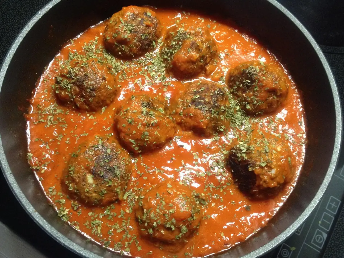 Meatballs simmering in tomato sauce in a skillet, similar to these homemade meatballs, showing how to make meatballs in sauce