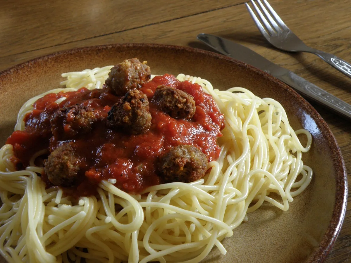 Spaghetti topped with tomato sauce and homemade meatballs on a plate