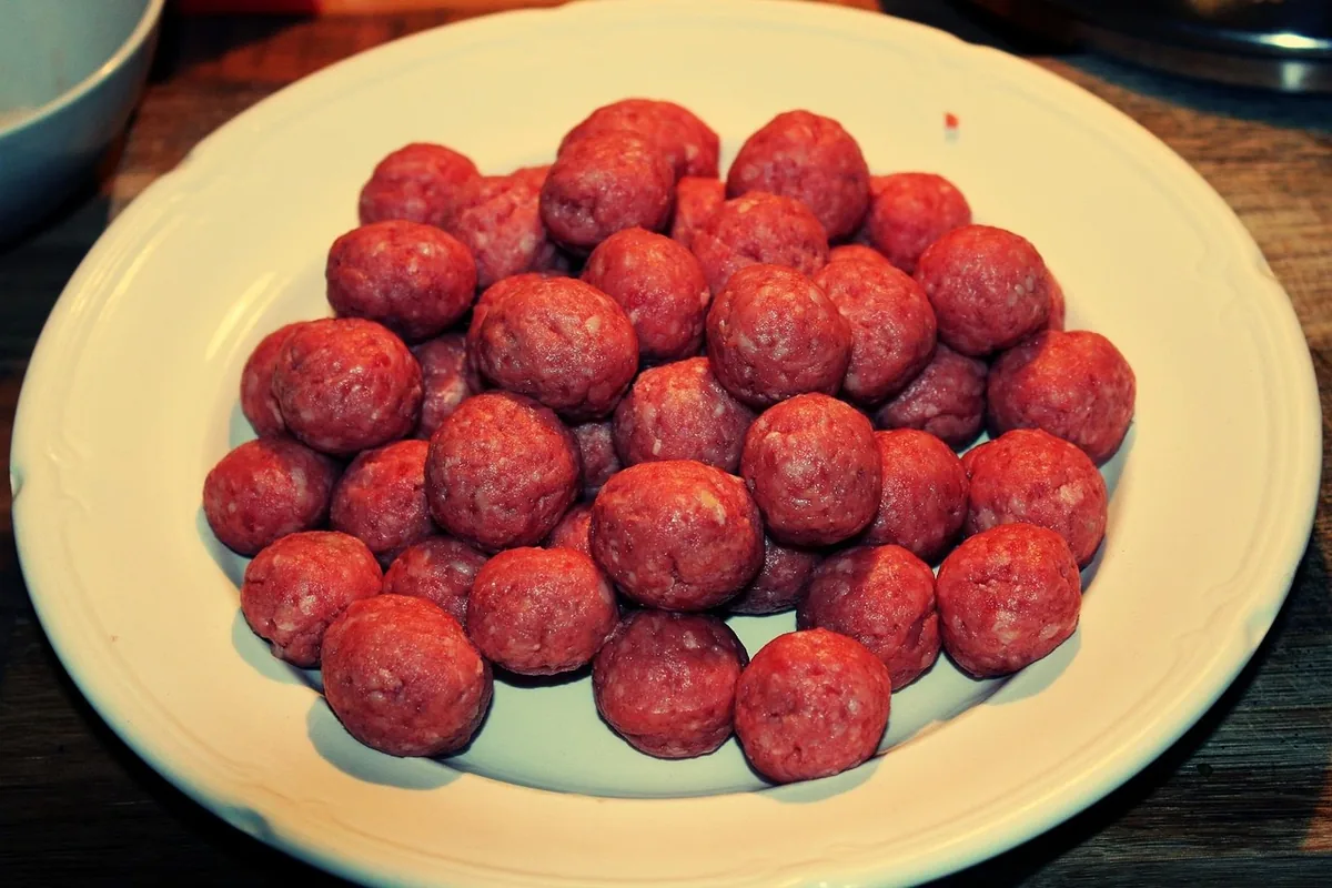 Raw shaped beef meatballs on a plate, ready to cook