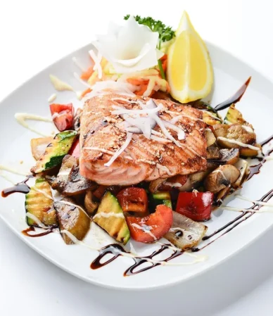 Glazed salmon fillet over roasted vegetables with a dark sauce drizzle, similar to this teriyaki salmon recipe
