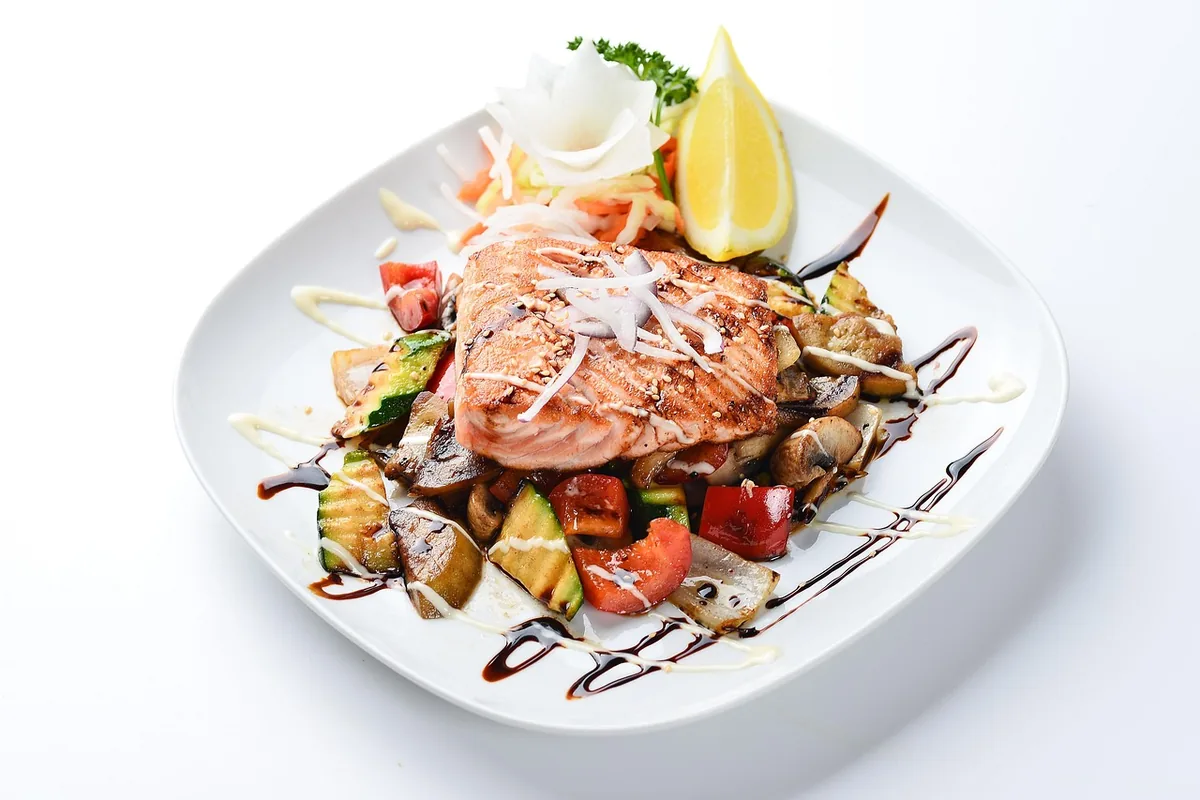 Glazed salmon fillet over roasted vegetables with a dark sauce drizzle, similar to this teriyaki salmon recipe
