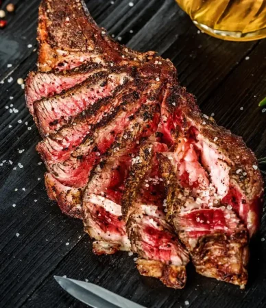 Sliced bone-in rib steak cooked medium-rare with peppercorns and rosemary, similar to this ribeye steak recipe