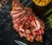 Sliced bone-in rib steak cooked medium-rare with peppercorns and rosemary, similar to this ribeye steak recipe