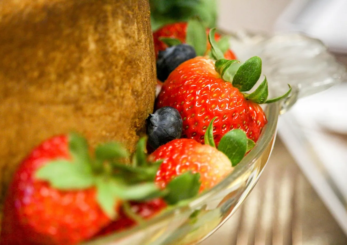Close-up of ripe whole strawberries and blueberries served beside a golden pound cake