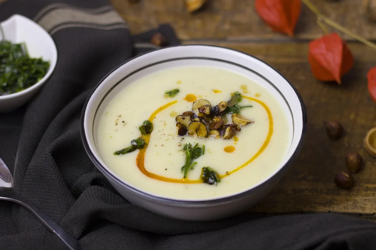 Bowl of creamy soup with a herb garnish, similar to chicken and gnocchi soup ready to serve