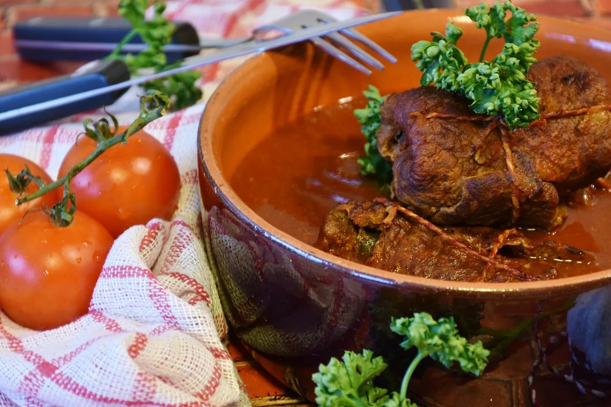 Braised beef in a rich tomato sauce in a clay pot with parsley, similar to this swiss steak recipe
