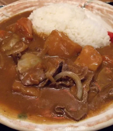Tender beef pieces and onions in brown gravy with white rice, similar to beef tips and gravy