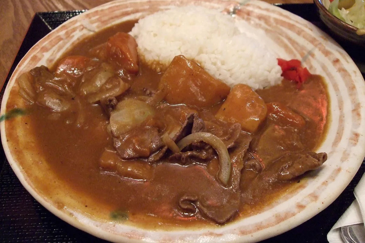 Tender beef pieces and onions in brown gravy with white rice, similar to beef tips and gravy
