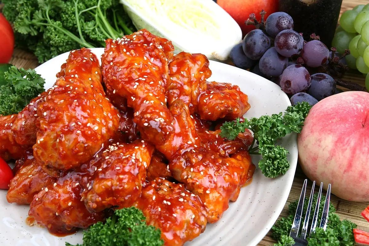 Glossy red gochujang-glazed chicken drumettes with sesame seeds on a white plate, similar to this Korean fried chicken recipe
