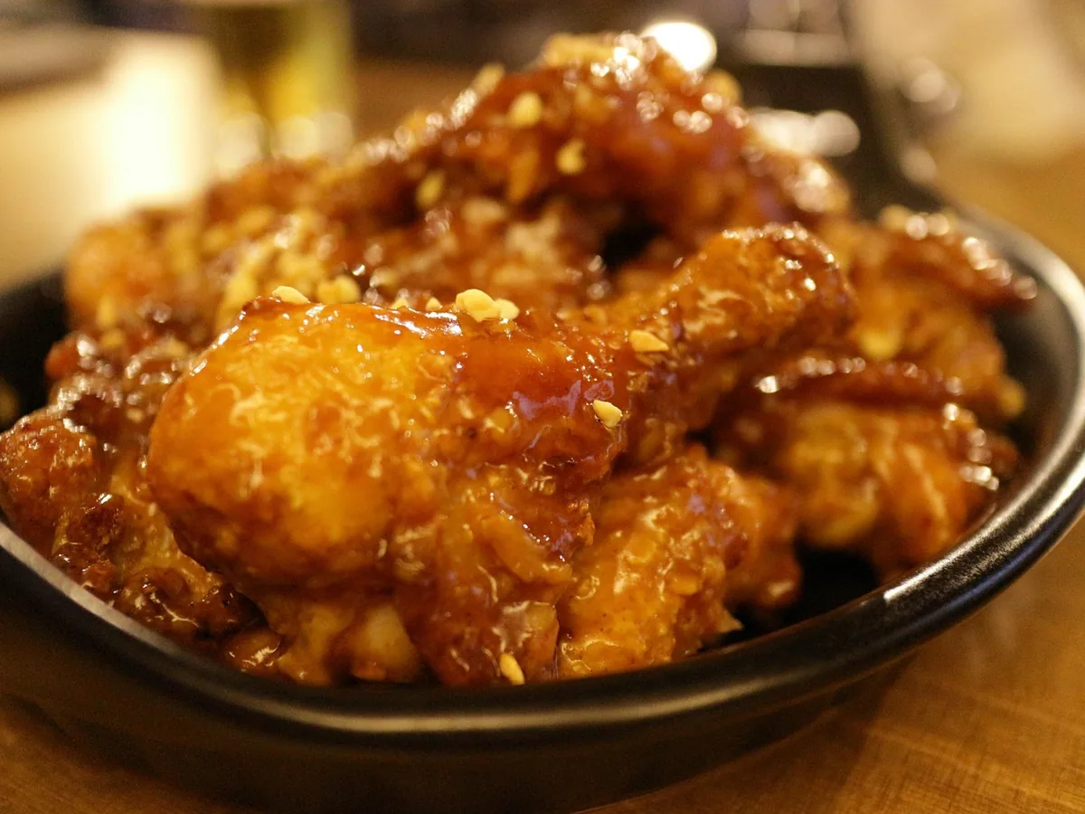 Sticky glazed Korean fried chicken pieces in a black bowl ready to serve