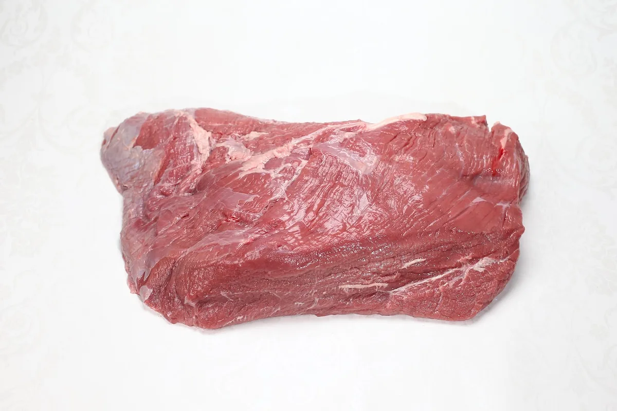 A lean, trimmed raw cut of beef round ready to be marinated and seared