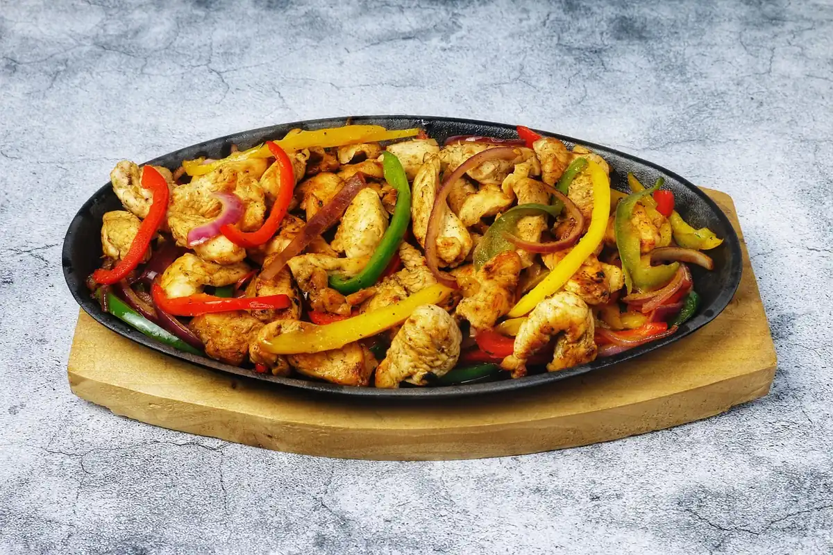 Chopped seared chicken with bell peppers and onion in a cast iron skillet, similar to this chipotle chicken recipe