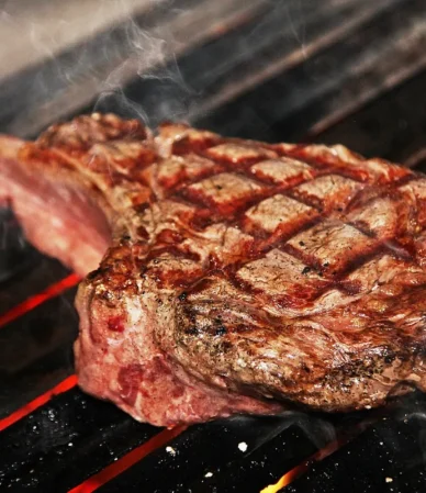 Thick tomahawk steak with crosshatch grill marks on hot grates, similar to the ribeye in this how to grill steak guide