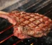 Thick tomahawk steak with crosshatch grill marks on hot grates, similar to the ribeye in this how to grill steak guide