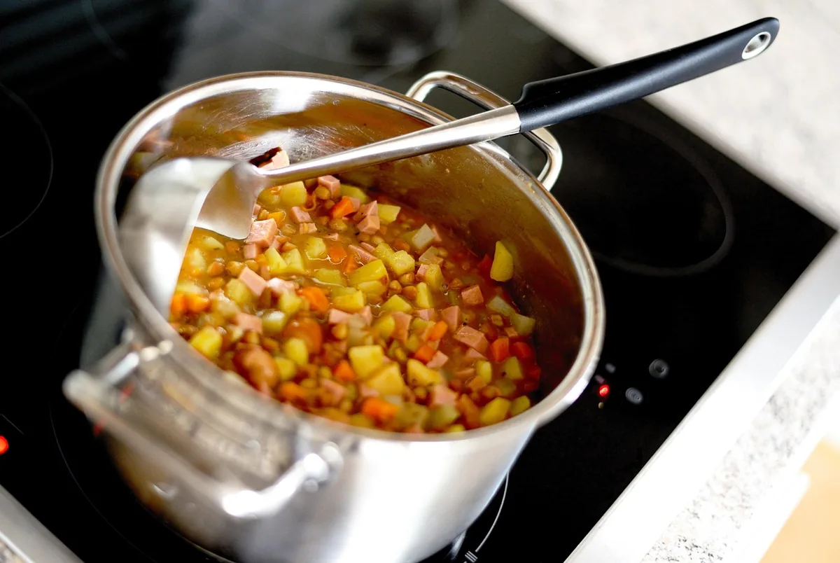 Pot of soup with corn and diced vegetables simmering on the stovetop