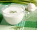 Glass cup of creamy white sauce topped with a dill sprig, similar to a lemon dill sauce for salmon