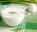 Glass cup of creamy white sauce topped with a dill sprig, similar to a lemon dill sauce for salmon