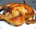 Golden roasted whole chicken with crisp, seasoned skin on a white plate, similar to beer can chicken
