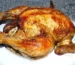 Golden roasted whole chicken with crisp, seasoned skin on a white plate, similar to beer can chicken