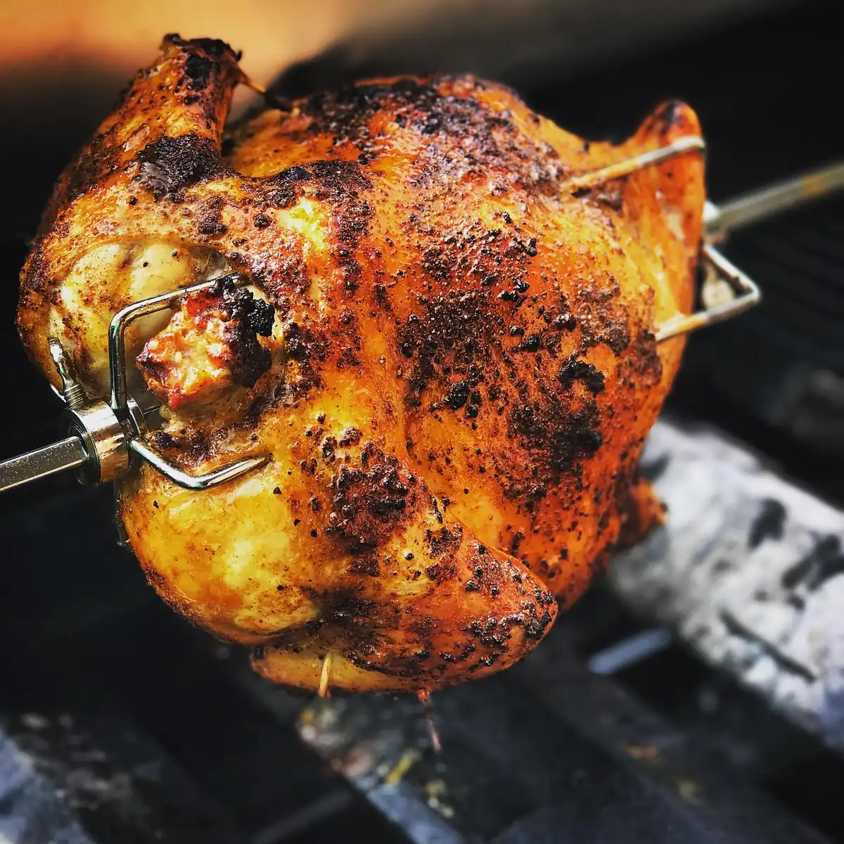 Spice-rubbed whole chicken with charred, crisp skin cooking over a hot grill