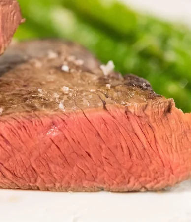 Thick steak cut open to show even pink from edge to edge with a browned crust and flaky salt, similar to how to reverse sear a steak
