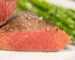Thick steak cut open to show even pink from edge to edge with a browned crust and flaky salt, similar to how to reverse sear a steak