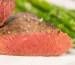 Thick steak cut open to show even pink from edge to edge with a browned crust and flaky salt, similar to how to reverse sear a steak