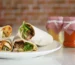 Flour tortilla wraps cut in half showing chicken and lettuce filling, similar to a buffalo chicken wrap