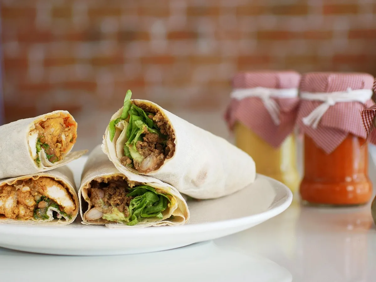 Flour tortilla wraps cut in half showing chicken and lettuce filling, similar to a buffalo chicken wrap