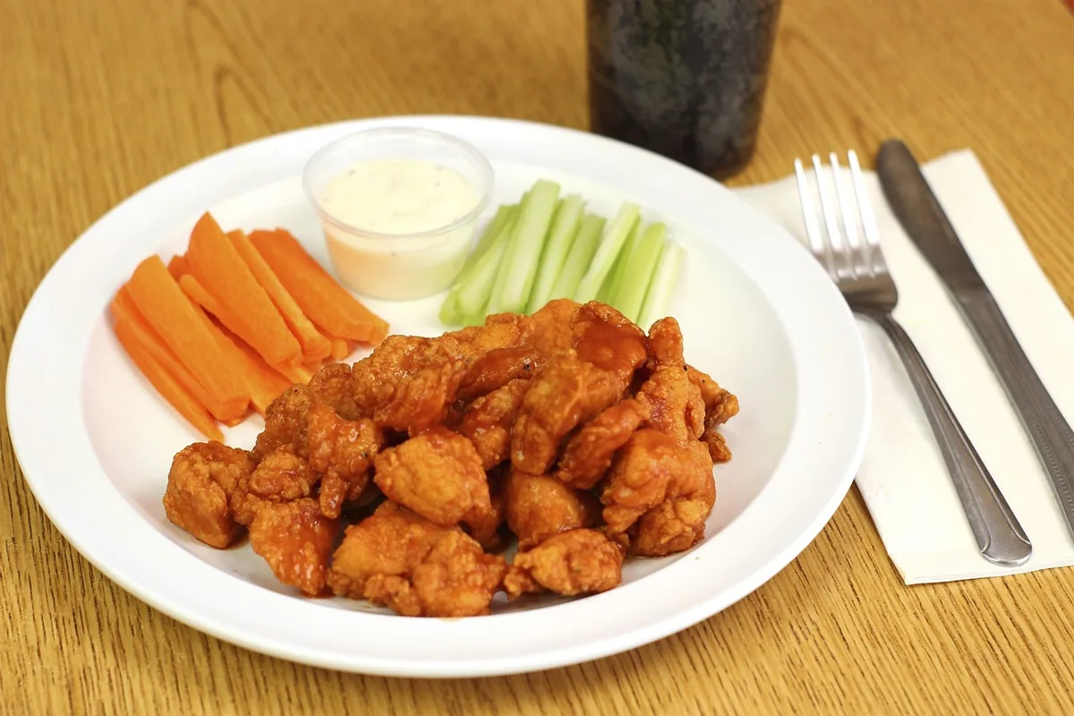 Crispy boneless chicken pieces in buffalo sauce with celery, carrots and ranch, similar to the filling for buffalo chicken wraps