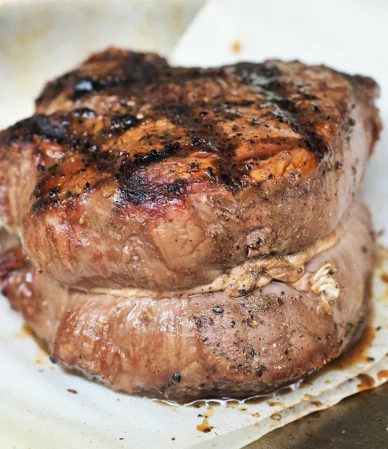Thick grilled tenderloin steak with a dark peppered crust, similar to the pan-seared filet mignon in this recipe
