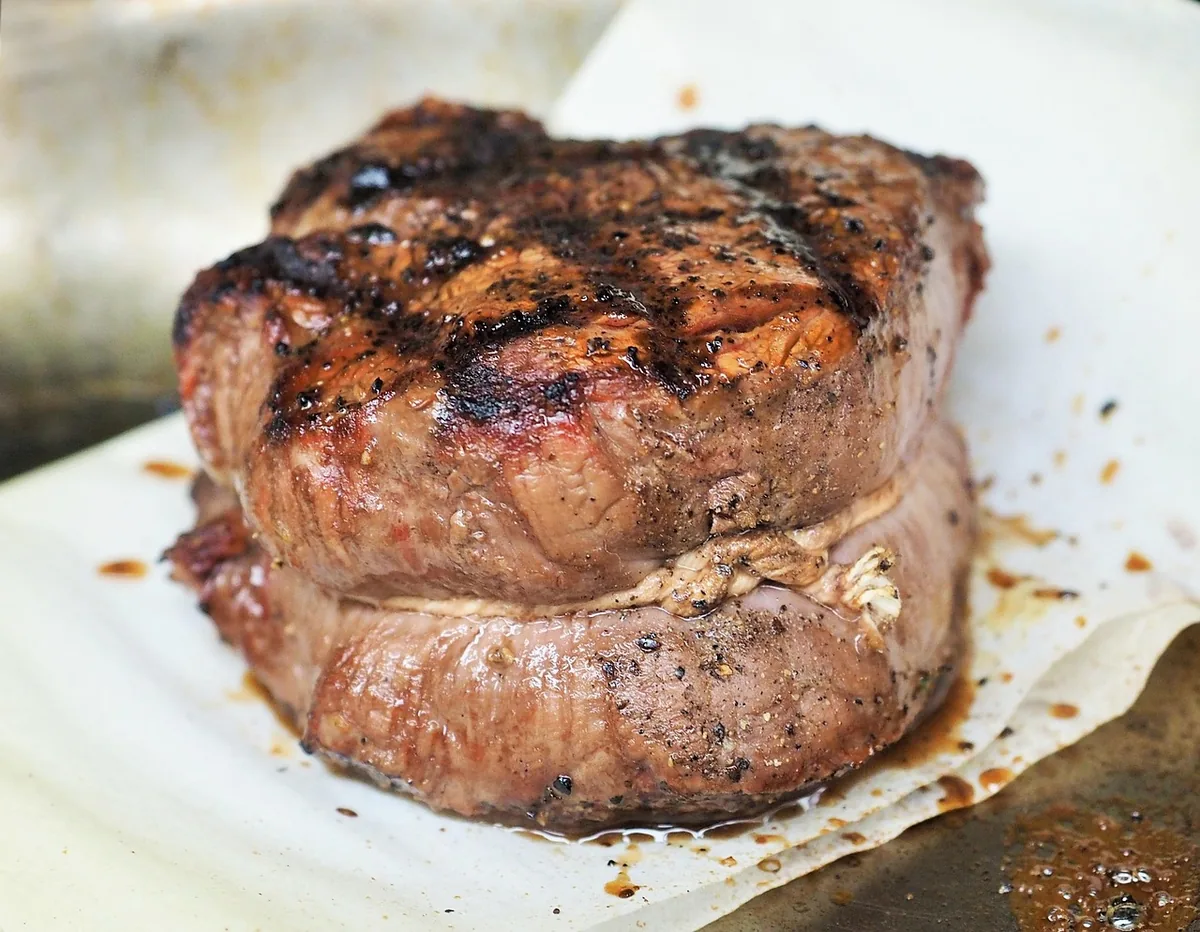 Thick grilled tenderloin steak with a dark peppered crust, similar to the pan-seared filet mignon in this recipe