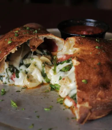 Golden stuffed calzone cut open to show a cheesy filling, similar to a homemade Costco chicken bake copycat