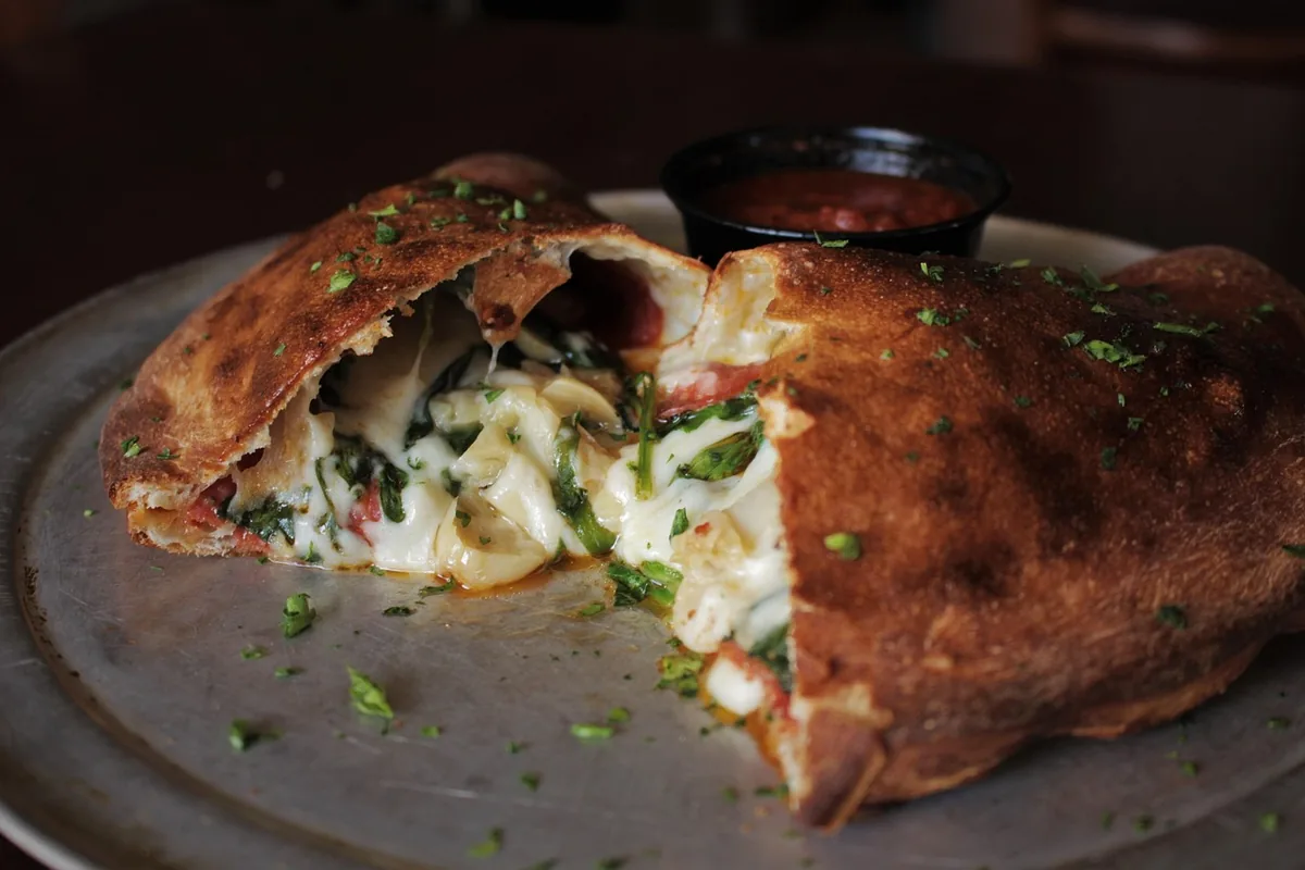 Golden stuffed calzone cut open to show a cheesy filling, similar to a homemade Costco chicken bake copycat