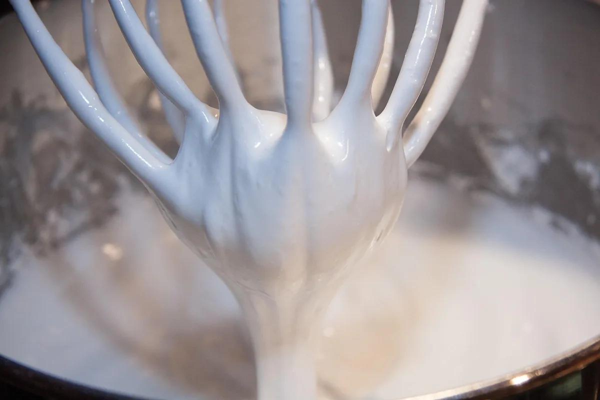 Firm glossy meringue clinging to a whisk, the base of fluffy souffle pancakes