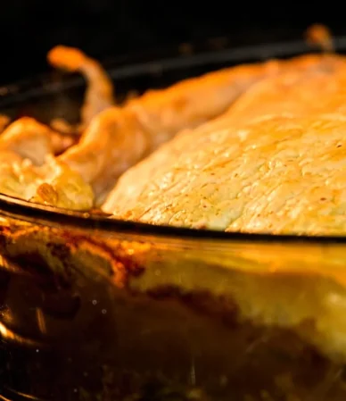 Golden baked crust bubbling in a glass baking dish in the oven, similar to this chicken cobbler recipe