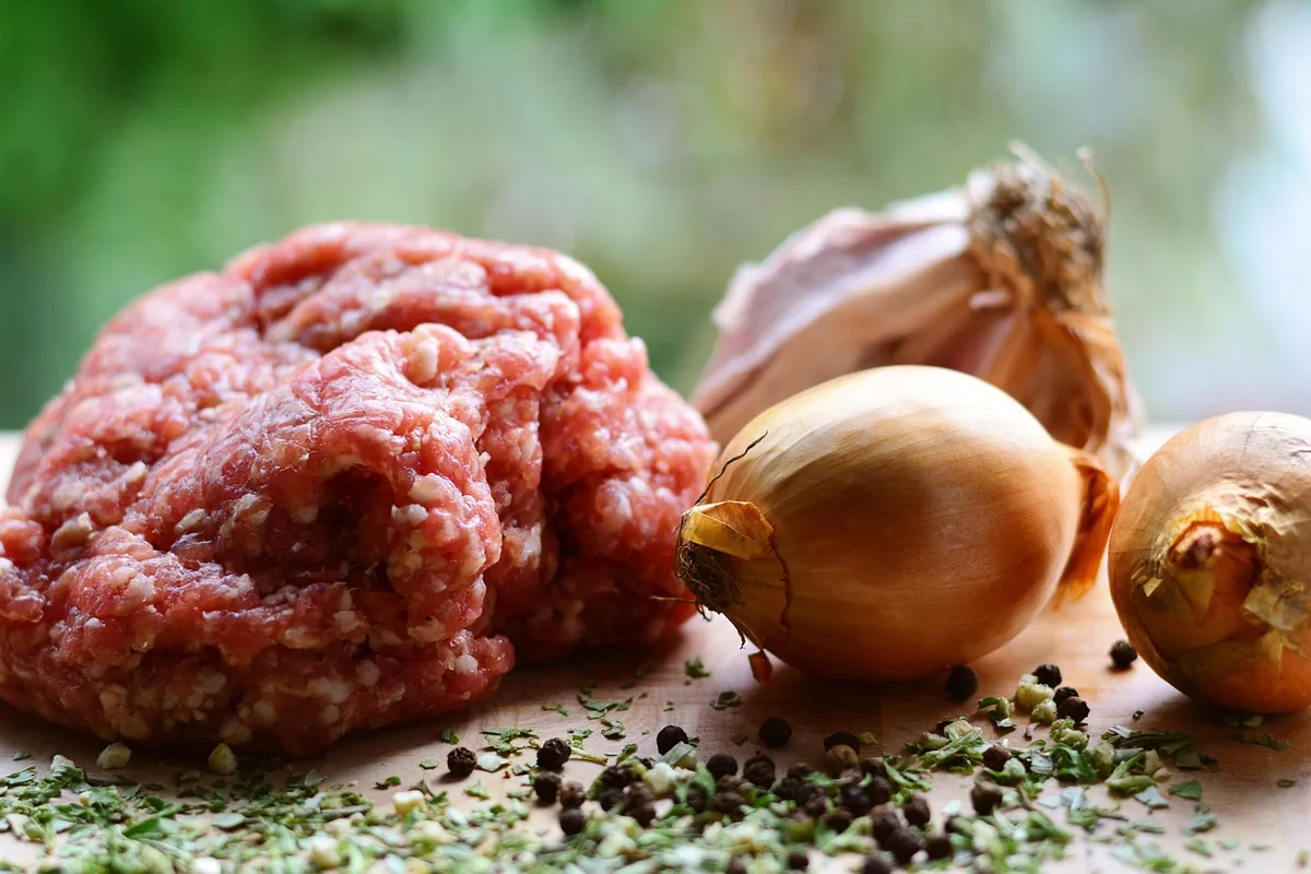 Raw ground beef with yellow onions and garlic, ready to brown for the meat sauce