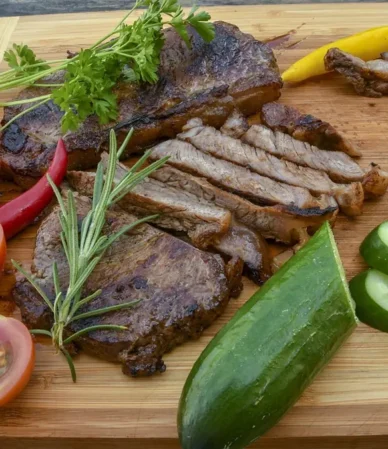 Sirloin tip steak sliced thin against the grain on a bamboo board with tomatoes, rosemary and cucumber, similar to this recipe