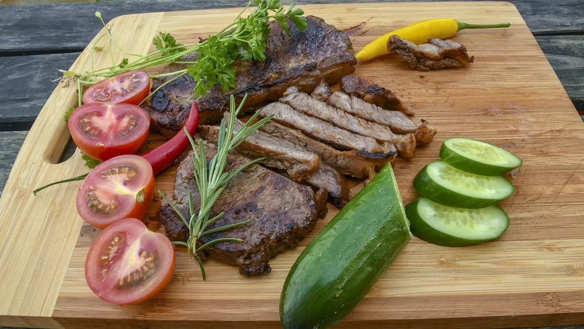 Sirloin tip steak sliced thin against the grain on a bamboo board with tomatoes, rosemary and cucumber, similar to this recipe